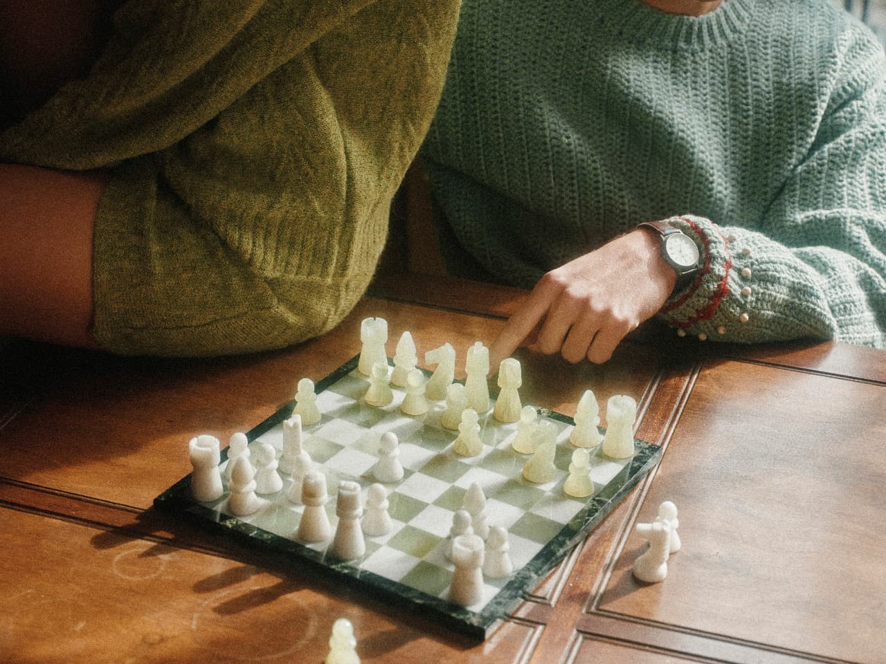 Two people playing chess at a wooden table